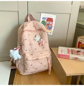 Close-up of pink quilted backpack with bow prints and cute star plush charms