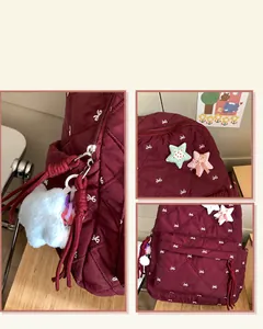 Detail view of burgundy quilted backpack featuring white bow prints and plush star charms