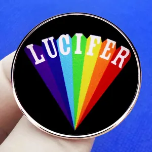LUCIFER rainbow enamel pin badge with rose gold metal edge on a blue textured background