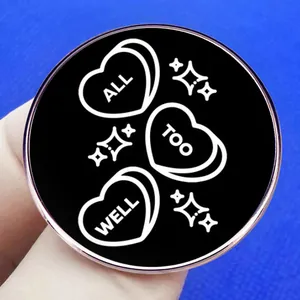 All Too Well black enamel round brooch with gold trim and white heart design