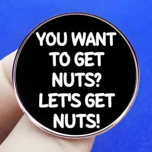 Round enamel pin with 'Let's Get Nuts' text and polished silver metal border