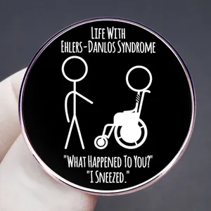 Badge rond noir avec citation sur le syndrome d'Ehlers-Danlos et dessin de bonhommes