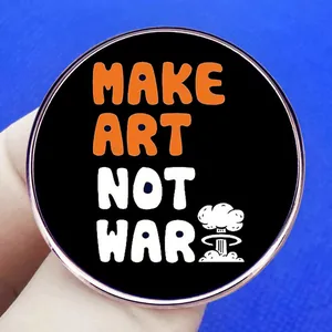 Round 'MAKE ART NOT WAR' metal badge pin with anti-war slogan on blue background