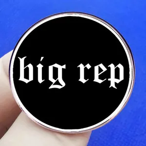 Καρφίτσα μουσικού άλμπουμ Big Rep με γοτθικά γράμματα κρατημένη στο χέρι
