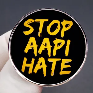 Stop AAPI Hate round enamel pin badge with black background and yellow lettering