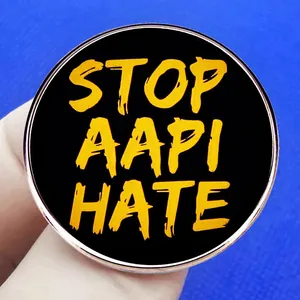 Stop AAPI Hate metal badge with yellow text on black background and silver metal frame