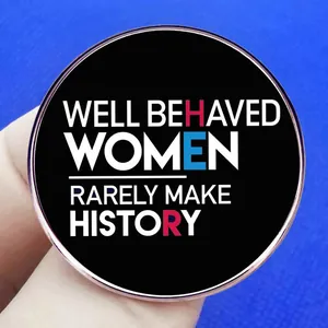 Round brooch with text Well Behaved Women Rarely Make History held by a hand
