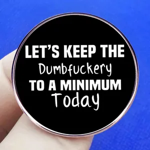 Round black enamel pin with Let's Keep the Dumbfuckery to a Minimum text and rose gold trim