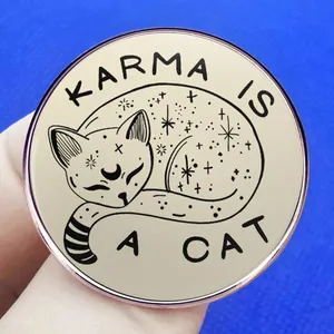 Round 'KARMA IS A CAT' enamel pin with black cat and moon illustration on beige