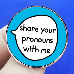 Inclusive blue round enamel pin with share your pronouns with me message on hand