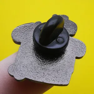 Close-up of enamel pin back with black rubber clutch and textured metal finish