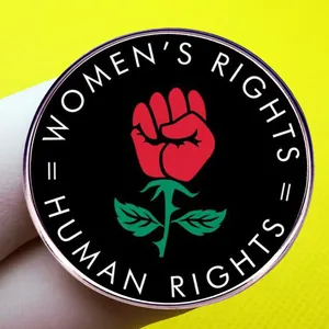 Épinglette féministe avec poing rose rouge sur fond jaune texturé pour droits des femmes