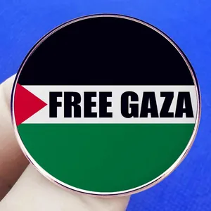 Chapa redonda de metal con bandera de Gaza y texto Free Gaza en mano con fondo azul