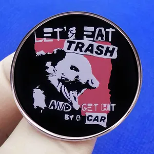 Enamel opossum pin with Let's Eat Trash meme text on a round metal badge accessory