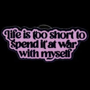 Badge en émail violet avec citation inspirante sur fond noir élégant et moderne