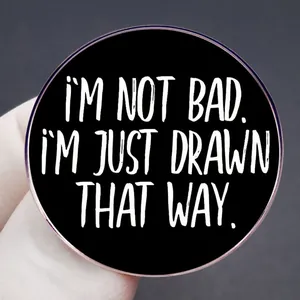 Round enamel pin featuring the quote I'm not bad I'm just drawn that way in black and white