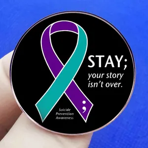 Enamel pin with purple teal ribbon and stay message for suicide prevention awareness
