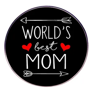 Detalle de una insignia redonda negra con 'WORLD'S best MOM' y un pequeño corazón rojo