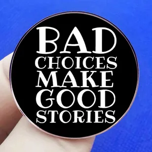 Badge rond noir avec citation Bad Choices Make Good Stories tenu entre les doigts