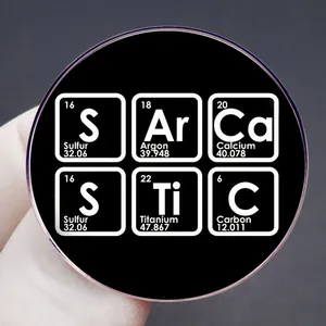Black round SArCaSTIC chemical element enamel pin badge held in hand for display
