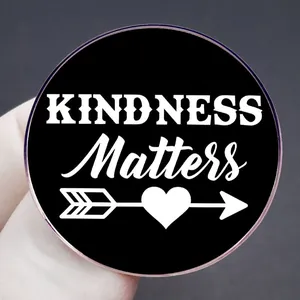 Round matte black brooch pin with white KINDNESS Matters text and heart arrow