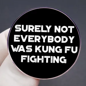Runder schwarzer Emaille-Anstecker mit weißem Kung-Fu-Spruch in der Hand gehalten