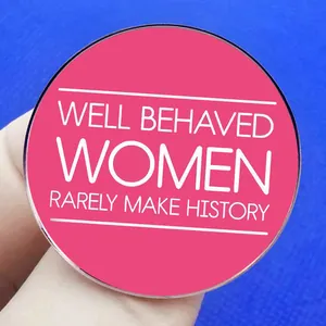Pink feminist brooch with WELL BEHAVED WOMEN RARELY MAKE HISTORY quote on blue background