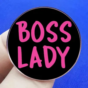 Black round Boss Lady pin badge with pink artistic font on a blue texture background