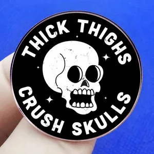 Thick Thighs Crush Skulls enamel pin with cracked white skull on black round badge
