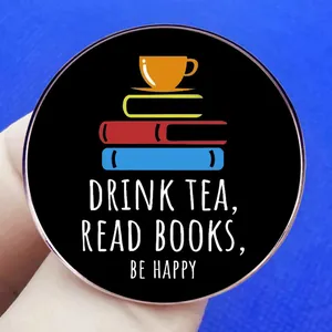 Drink tea and read books metal pin badge featuring a stack of colorful books and text