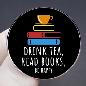 Enamel pin featuring a tea cup and stacked books with a happy life slogan design