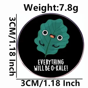 Round black enamel kale brooch pin with Everything Will Be O-Kale pun and cartoon art