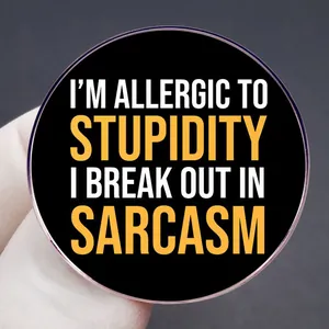 Round black enamel pin featuring funny I'M ALLERGIC TO STUPIDITY text design
