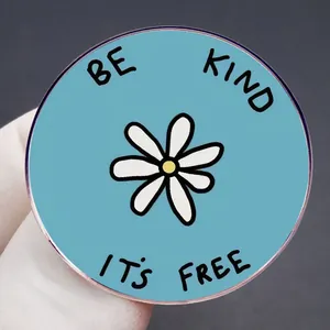 Badge en émail bleu avec marguerite et citation Be Kind It's Free en main