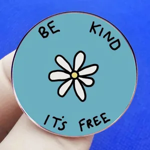 Broche tournesol bleue avec texte Be Kind It's Free tenue sur fond bleu texturé