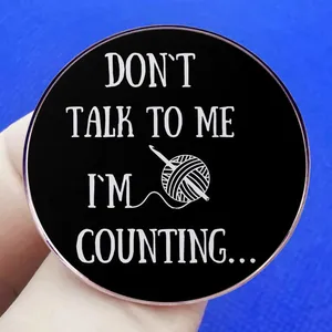 Black enamel pin featuring knitting yarn and Don't Talk To Me I'm Counting text