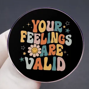 Pop art round badge with YOUR FEELINGS ARE VALID text and floral pattern held in hand