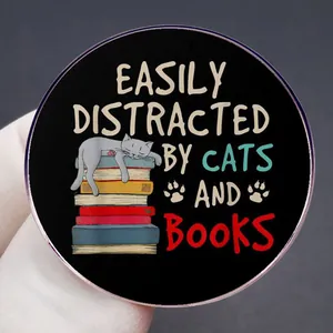 Round metal badge featuring a cute cat on books with Easily Distracted by Cats and Books text
