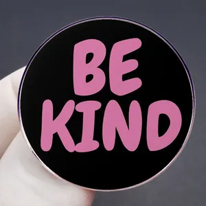 Pink Be Kind enamel pin badge held in hand showing round black metal alloy design