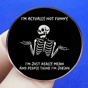 Black round enamel pin with skull and 'I'm just mean' text on blue background