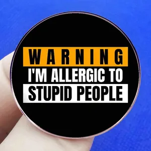 Broche sarcastique I'm Allergic to Stupid People en métal tenue à la main
