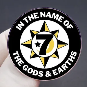Black and gold round enamel pin featuring 7 stars moon emblem held by hand for size