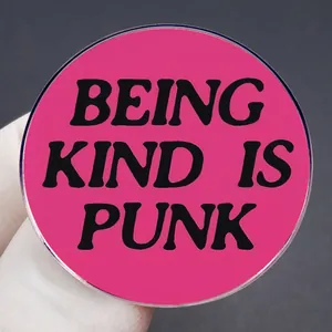 Hot pink round brooch featuring black Being Kind Is Punk text lettering