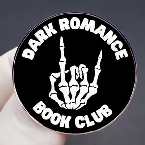 Dark Romance Book Club round enamel pin featuring a white skeleton hand gesture