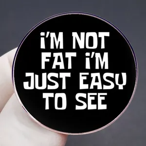 Broche ronde noire humoristique avec citation 'I'M NOT FAT I'M JUST EASY TO SEE' en métal