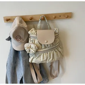 Detail of beige pleated nylon backpack with mini pouch hanging on a wooden hook