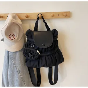 Detail van zwarte geplooide nylon rugzak met leren klep en extra klein tasje eraan