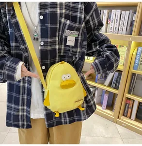 Detail of yellow canvas duck crossbody bag with adjustable strap worn by a model