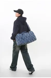 Grand sac de voyage en denim bleu marine matelassé porté par un mannequin stylé