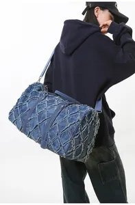 Détail du grand sac de voyage en denim matelassé avec bords effilochés sur un modèle